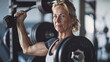 © mahamad - Fit mature woman lifting weights in a gym