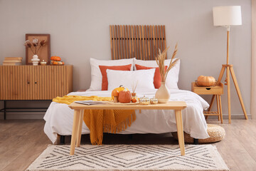 Poster - Interior of modern bedroom with soft bed, chest of drawers and pumpkins on coffee table