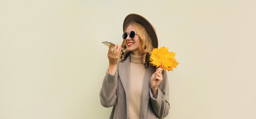 Wall Mural - Autumn portrait of happy smiling young woman calling on phone, stylish girl talking on a smartphone