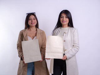 two happy Hispanic girls holding paper gift bags, smiling.