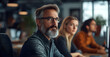 © ClicksdeMexico - A man with glasses and a beard is sitting in a room with other people