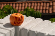 © AnaPliego - calabaza naranja de plástico sobre balcón con fondo de tejas de casa a la luz del día