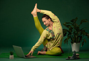 woman meditating doing yoga poses in green sari on green background