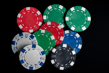 Poker chips of all colors randomly placed on a black background