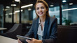 © halo - Portrait of a businesswoman sitting at an office table, smiling and holding her tablet in front of the camera.