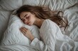 © Olsek - A serene young woman sleeps peacefully on a soft white pillow. The cozy setting creates a calm atmosphere. Perfect for relaxation or wellness themes. Generative AI