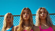 © vanAmsen - Three determined young female athletes, standing in front of a chain-link fence on a bright, sunny