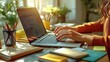 © LuvTK - A detailed close-up of a woman’s fingers on a laptop keyboard, with notebooks, pens, and sticky notes scattered across the desk, sunlight gently filtering through the window onto the work area.