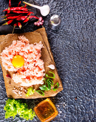 Canvas Print - Raw minced meat in bowl on dark table and ingredients.