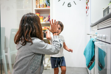 A woman and a child are high fiving each other in a kitchen