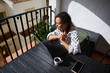 © Taras Grebinets - Woman working remotely on a laptop outdoors, enjoying a sunny day on a balcony with a coffee
