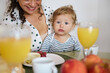 © Taras Grebinets - Mother and child enjoying breakfast together at home, with fresh fruit and juice, creating a warm family moment filled with love and connection