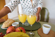 © Taras Grebinets - Woman preparing a healthy breakfast with fresh orange juice, apples, and bread on a green placemat