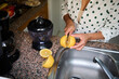 © Taras Grebinets - Woman in a polka dot shirt preparing fresh lemon juice in a modern kitchen setting