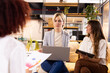 © Wavebreak Media - Discussing creative writing ideas, multiracial women using laptop and tablet in modern office