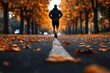 © teera - A solitary runner jogs along a peaceful autumn road adorned with fallen leaves, capturing the essence of seasonal fitness.
