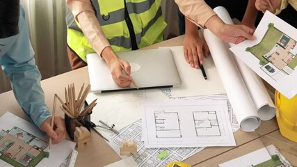 Wall Mural - Smart architect and safety engineer discussion about building blueprint on table with architectural document, measurement tools and wooden block scatter around at modern office. Closeup. Delineation.