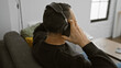 © Krakenimages.com - A man in casual attire relaxes at home on a couch listening to music with headphones, providing a cozy and modern ambiance.