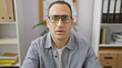 © Krakenimages.com - Portrait of a serious professional man in glasses with office background of shelves and binders.