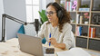 © Krakenimages.com - Hispanic woman records podcast in a cozy studio with modern equipment