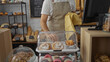 © Krakenimages.com - Baker working in a bakery shop arranging pastries and bread, hispanic male hands seen behind the counter in an indoor setting