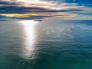 Wall Mural - Aerial view of ocean and island at sunset