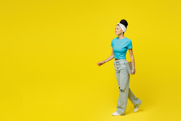 Wall Mural - Full body side view Latin IT woman she wears blue top t-shirt headband casual clothes hold closed laptop pc computer look camera isolated on plain yellow background studio portrait. Lifestyle concept.