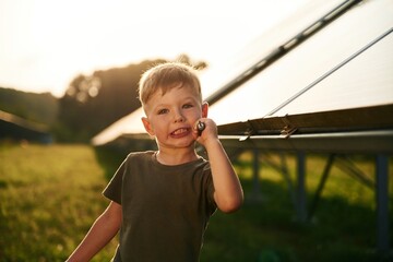 Little boy is with solar panels outdoors