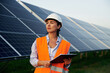 © standret - Checking the data, with notepad. Female worker engineer in uniform is near solar panels