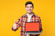 © ViDi Studio - Young IT man wears red checkered shirt casual clothes hold use work on laptop pc computer with blank screen workspace area show thumb up isolated on plain yellow orange background. Lifestyle concept.