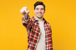 © ViDi Studio - Young smiling happy man he wear red checkered shirt casual clothes hold car key fob keyless system stretch hand to camera isolated on plain yellow orange background studio portrait. Lifestyle concept