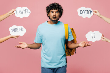 Young Indian boy student wear blue t-shirt casual clothes backpack bag read cards choose professions IT doctor manager lawyer isolated on plain pink background. High school university college concept.