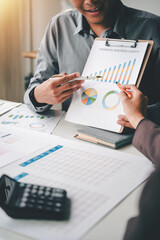 Wall Mural - Junior colleagues meet to discuss business charts and analytical investment budgets using calculators and laptops to calculate financial, tax, accounting, statistics, and analytical research ideas.