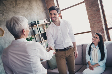 Wall Mural - Portrait of young married couple handshake greeting lady consultation visit psychotherapist loft interior office indoors