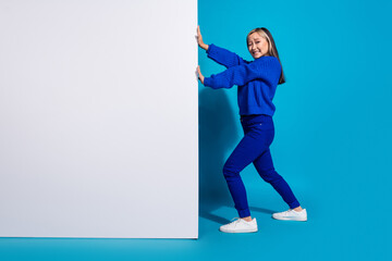 Poster - Photo portrait of trendy korean girl pushing huge advertisement billboard empty space promo information isolated on blue color background