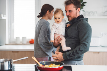 Happy young family cooking together in kitchen with baby.