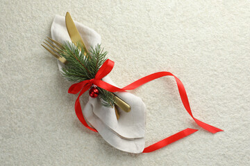 Wall Mural - Christmas table setting. Cutlery, napkin, ribbon, fir branches and bauble on light textured background, top view