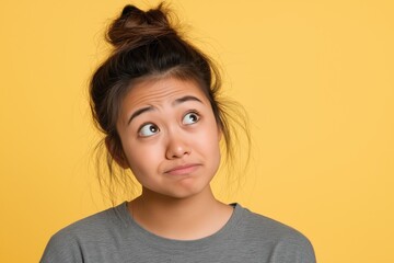 A studio close-up portrait of a young Asian woman wearing a casual t-shirt, with a colourful background.