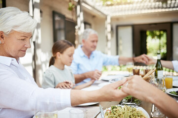 Family, holding hands and grandmother praying for food, thanksgiving and holiday celebration with child. Grace, lunch and people together for gratitude, blessing and eating with generations at home