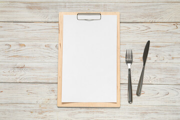 Poster - Clipboard with empty paper for menu design and cutlery on wooden table, flat lay