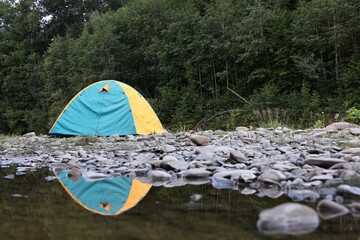 Canvas Print - Camping tent on stones near river in mountains