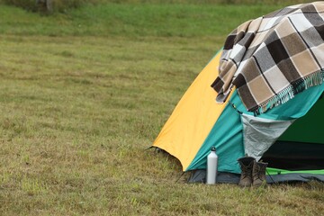 Wall Mural - Camping tent and tourist stuff on green grass in mountains, space for text