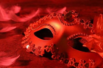 Poster - Beautiful carnival mask on table in red light, closeup