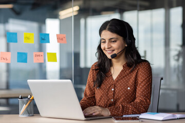 young beautiful online support worker at workplace, hispanic woman using headset phone for video cal