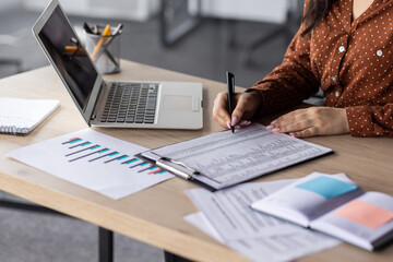 Wall Mural - Hands of financier close-up, female accountant on paper work, fills forms, and enters data into forms, reconciles financial reports, uses calculator and laptop, writes reconciliation results.