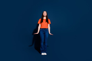 Photo of glad adorable cheerful woman wear orange outfit look empty space isolated on dark blue color background