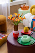 © FollowTheFlow - A cozy corner featuring vibrant flowers and warm accents, including an orange glass dish and bold graphic art. A blend of modern and vintage vibes.