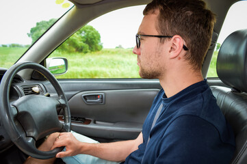 Young adult man driving the car and looking at road