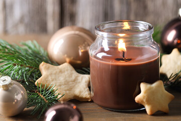 Poster - Burning candle, baubles, cookies and fir branches on wooden table, closeup. Christmas atmosphere