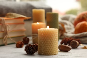 Wall Mural - Burning candles, books and autumn decor on grey wooden table